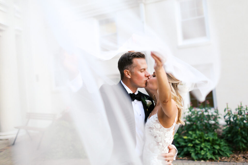 Newlyweds share a kiss under soft golden light on the golf course, photographed by Minneapolis wedding photographer.