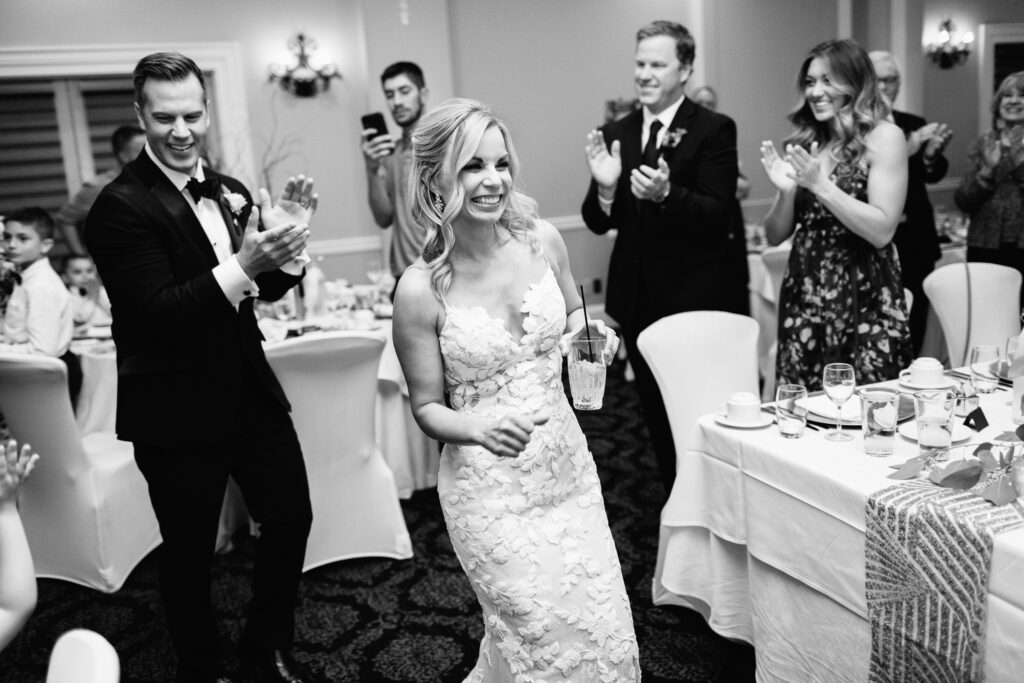 Guests cheering as bride and groom enter their reception with smiles and energy.