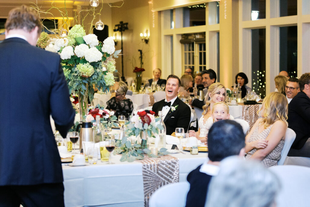 Bride and groom laughing during heartfelt speeches with Alive Studios DJing in the background.