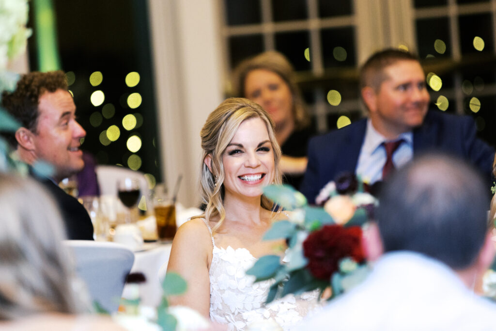 Bride laughing during heartfelt speeches.