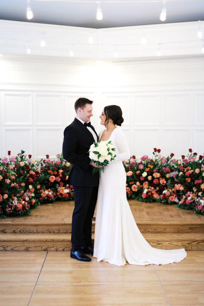 Bride and groom hold hand and look at eachother with laughter and joy at St. Paul College Club by Minnesota wedding photographer.