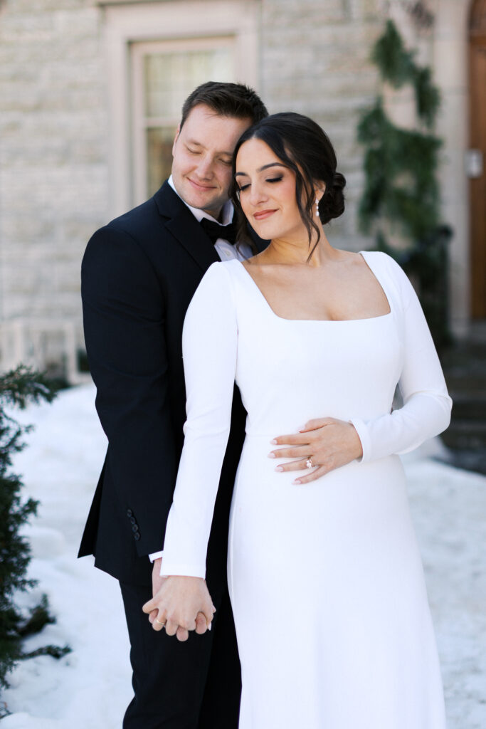 Romantic bride and groom portraits with their eyes closed in a moment in snow at St. Paul College Club by Minneapolis wedding photographer.