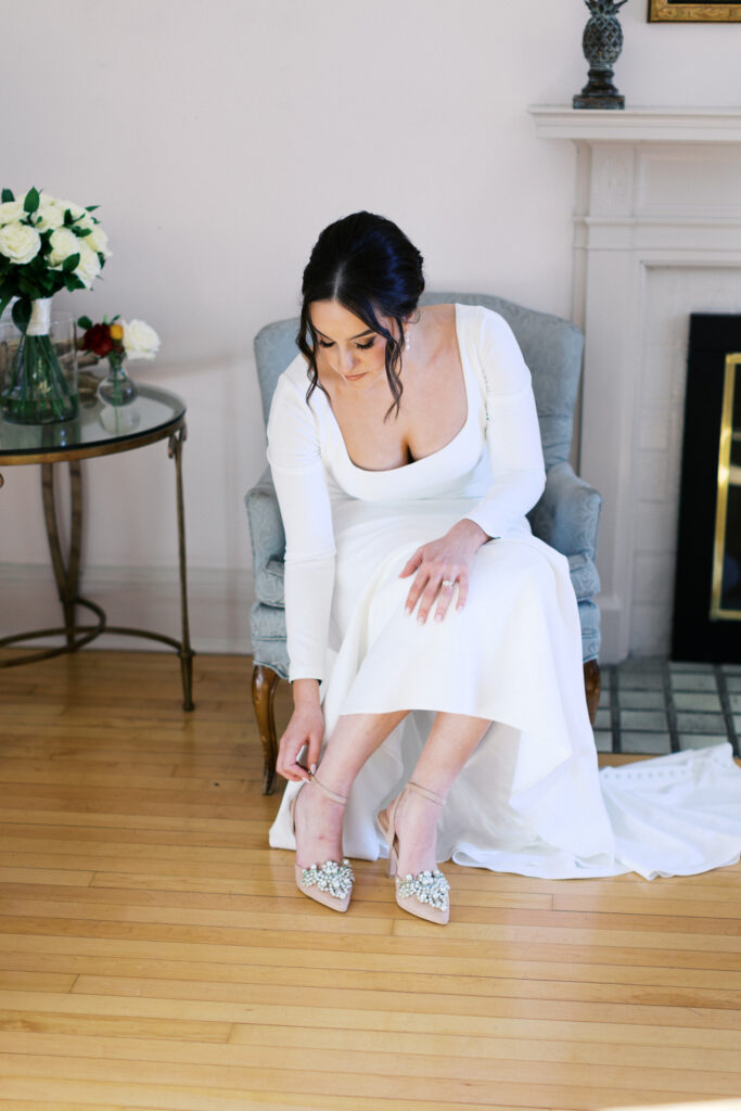 Bride putting on her wedding shoes at St. Paul College Club by Minnesota wedding photographer.