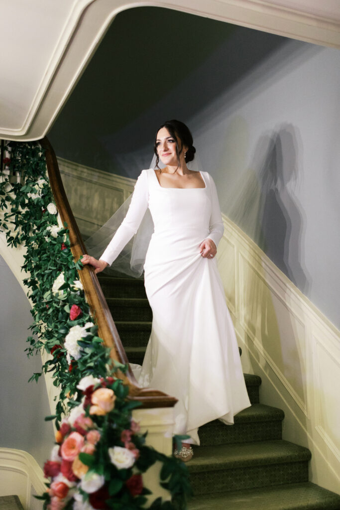 Bride in her elegant dress and luxury style walking down the stairs at St. Paul College Club by Minnesota wedding photographer.