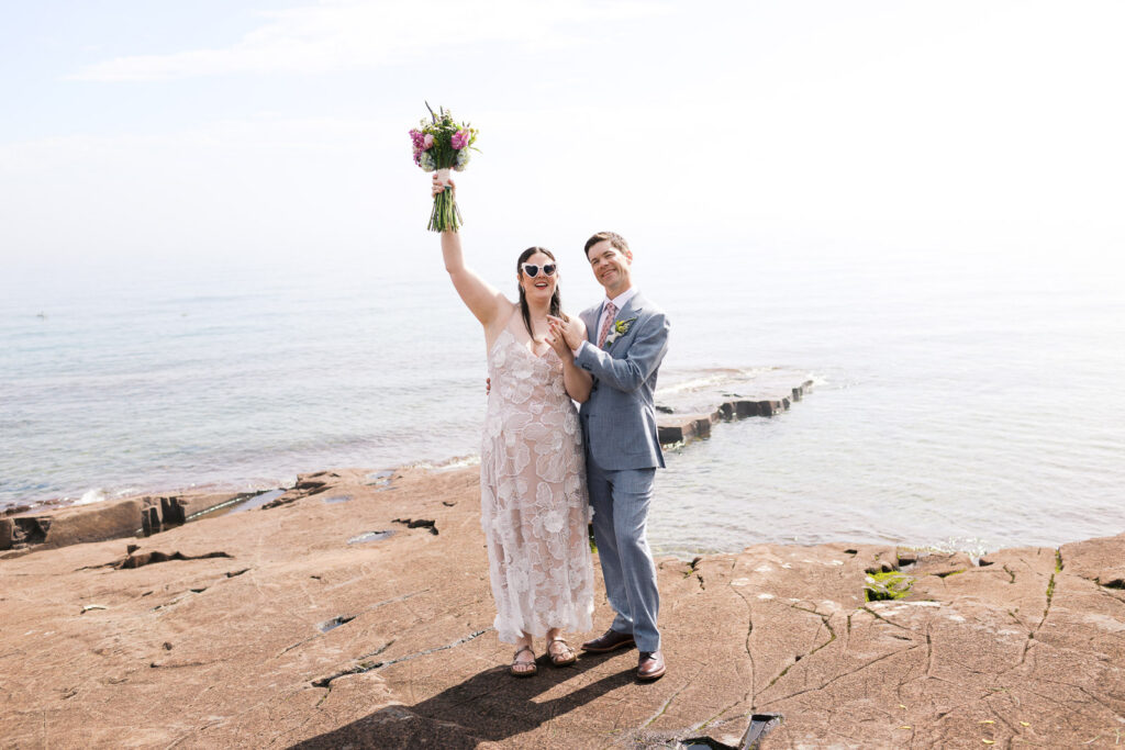 Bride and groom celebrate their marriage on the rocky shoreline of Lake Superior in Grand Marais, photographed by Toly Dzyuba Photography.
